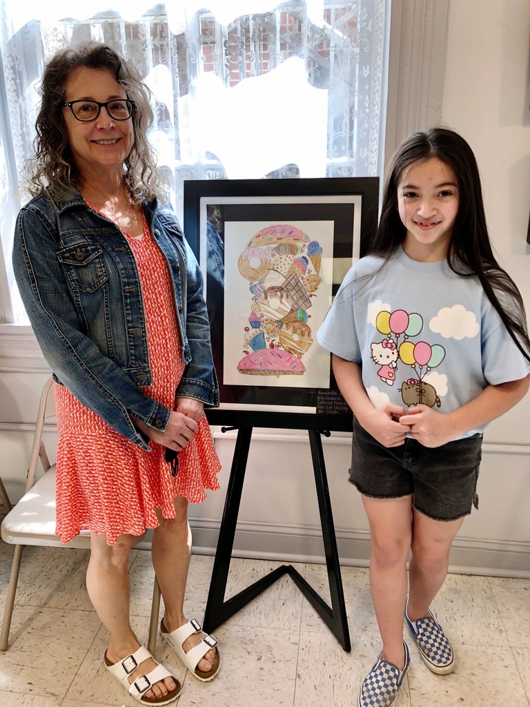 JCS student and teacher standing in front of the student's portrait at a local art show