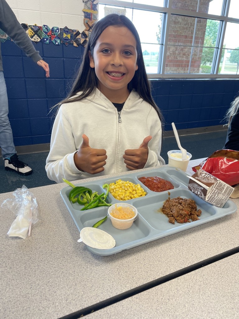 Female student giving two thumbs with her lunch tray